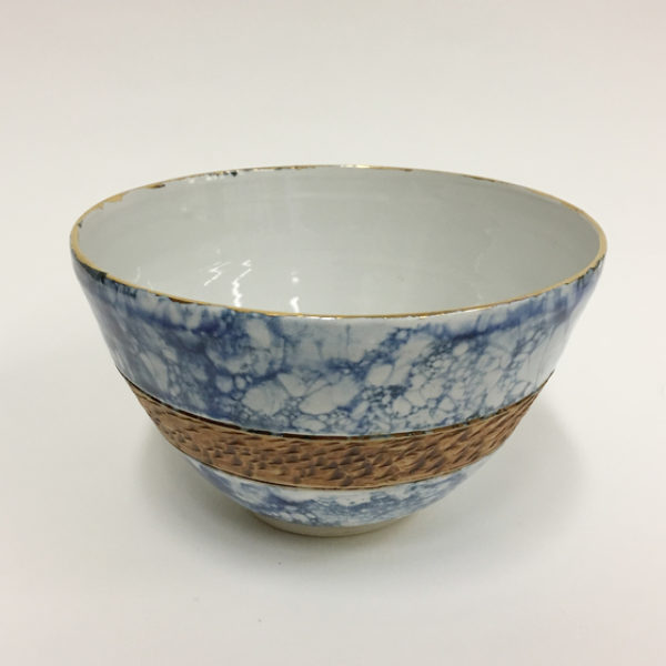 A ceramic bowl that has a blue and white marble pattern on the exterior surface with a band of red.